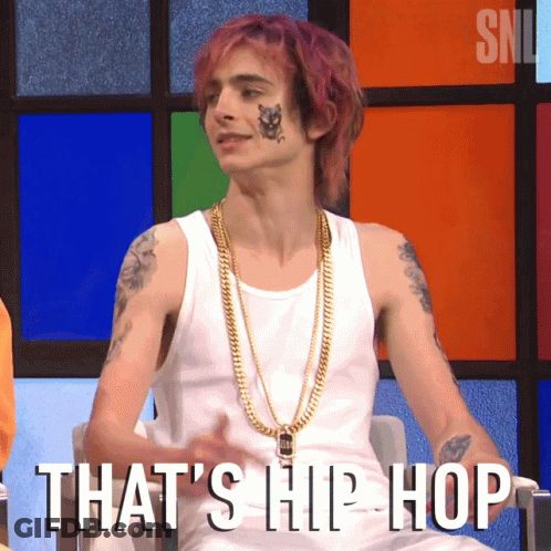 A Man With Purple Hair Is Wearing A White Tank Top And Gold Chains With The Words That 'S Hip Hop Written Below Him GIF