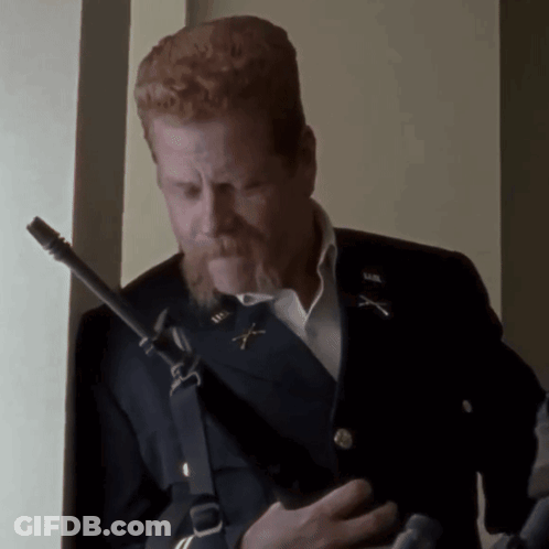 A Man With Red Hair And A Beard Is Holding A Gun And Wearing A Military Uniform GIF