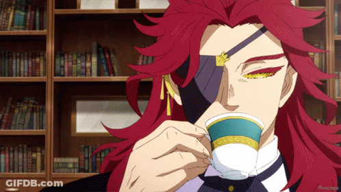 A Man With Red Hair Is Drinking From A Cup In Front Of Bookshelves GIF