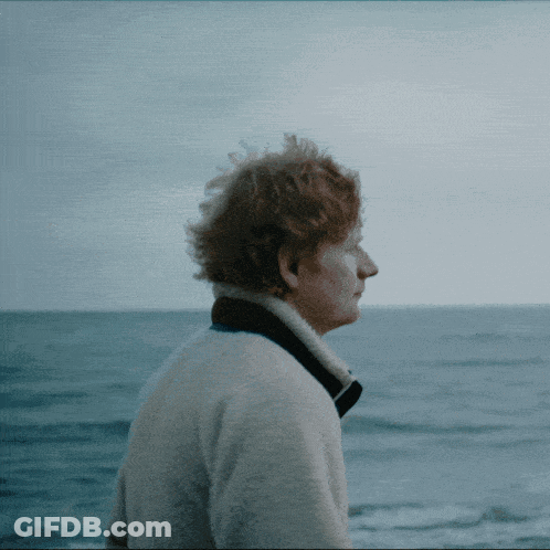 A Man With Red Hair Is Looking Out Over The Ocean GIF