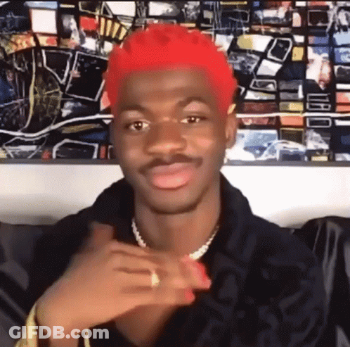 A Man With Red Hair Is Sitting In Front Of A Painting And Making A Face . GIF