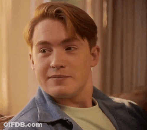 A Man With Red Hair Is Sitting On A Couch And Smiling . GIF