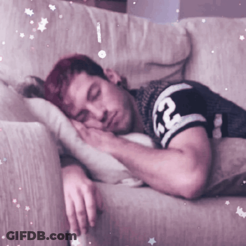 A Man With Red Hair Is Sleeping On A Couch With A Shirt That Says Rc On It GIF