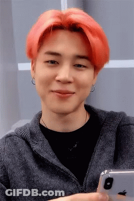 A Man With Red Hair Is Smiling While Holding An Apple Iphone GIF