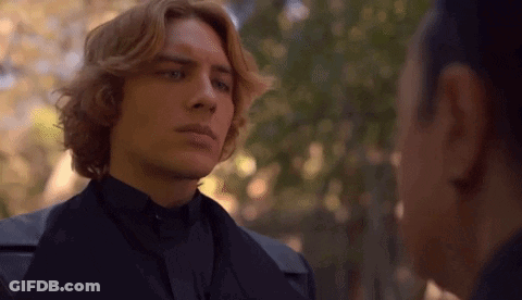 A Man With Red Hair Is Standing Next To A Woman In A Black Suit . GIF