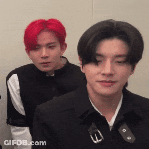 A Man With Red Hair Is Standing Next To Another Man In A Black Jacket GIF