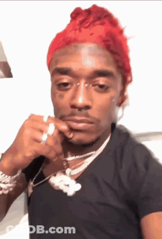 A Man With Red Hair Is Wearing A Black Shirt And A Silver Necklace GIF