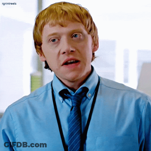 A Man With Red Hair Is Wearing A Blue Shirt And Tie With A Lanyard Around His Neck .. GIF