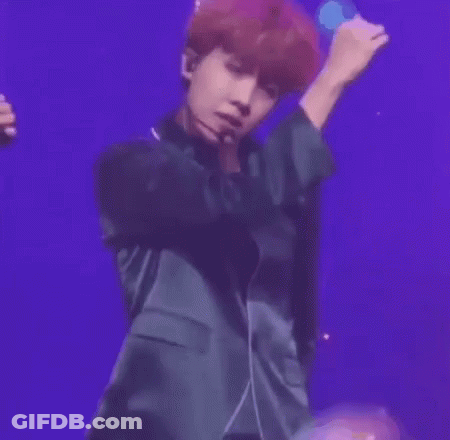 A Man With Red Hair Is Wearing A Microphone And Smiling While Standing On A Stage . GIF