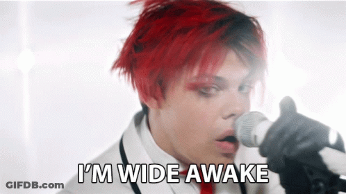 A Man With Red Hair Singing Into A Microphone With The Words " I 'M Wide Awake " Behind Him GIF