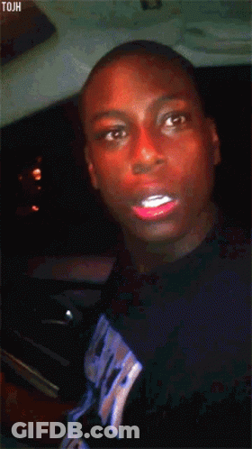 A Man With Red Lipstick On His Lips Is Wearing A Black Shirt With The Word Tjah On It GIF