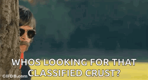 A Man With Sunglasses And A Mustache Is Peeking Out From Behind A Tree And Asking Who Is Looking For That Classified Cru GIF