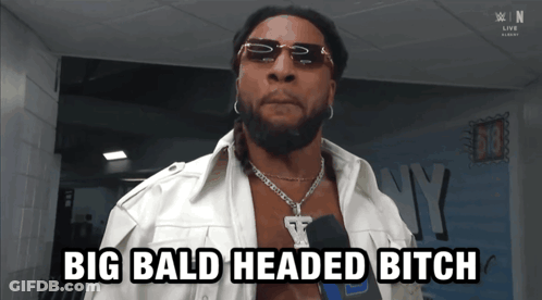 A Man With Sunglasses And A Necklace Says Big Bald Headed Bitch GIF