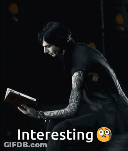 A Man With Tattoos Is Reading A Book In The Dark GIF