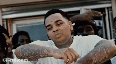 A Man With Tattoos On His Arms Is Standing In Front Of A Group Of People . GIF