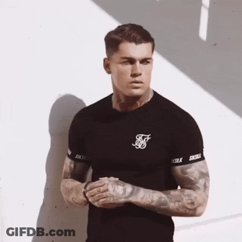 A Man With Tattoos On His Arms Is Wearing A Black Siksilk T-Shirt . GIF