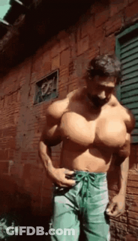 Muscular Man Standing In Front Of Brick Wall GIF