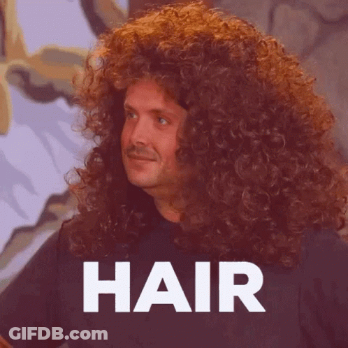 A Man With Very Long Curly Hair Is Standing In Front Of The Word Hair . GIF