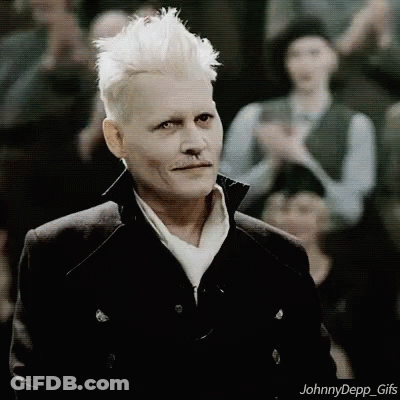 A Man With White Hair And A Nose Ring Is Standing In Front Of A Crowd And Looking At The Camera . GIF