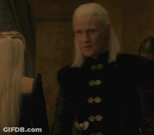 A Man With White Hair Is Wearing A Black Jacket With Buttons GIF
