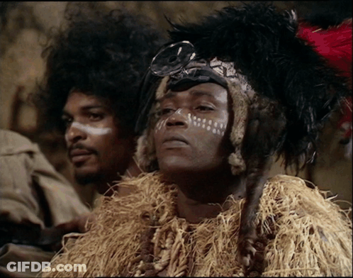 A Man With White Paint On His Face And A Feathered Headdress GIF