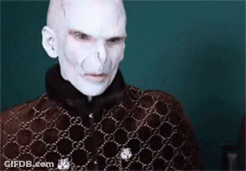 A Man With White Paint On His Face Is Wearing A Brown Jacket With A Gucci Pattern . GIF