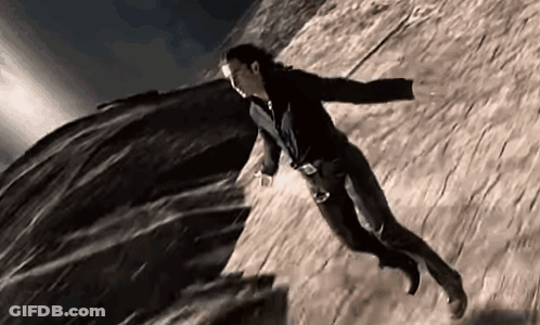 A Man With Wings Is Flying Through The Air Over A Rock . GIF