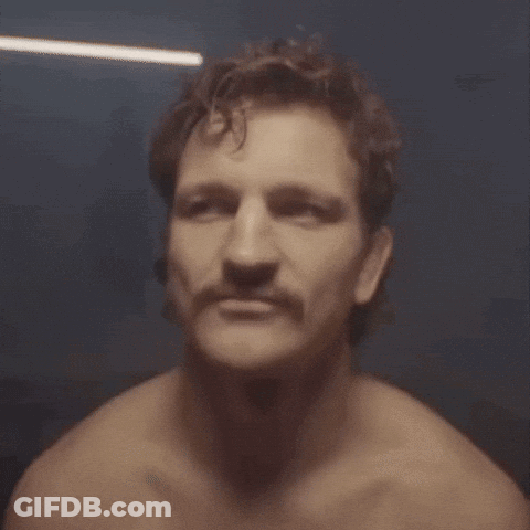 A Man Without A Shirt Has A Mustache And Looks At The Camera GIF