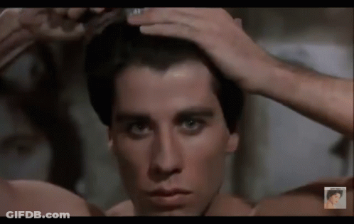A Man Without A Shirt Is Brushing His Hair In Front Of A Mirror GIF