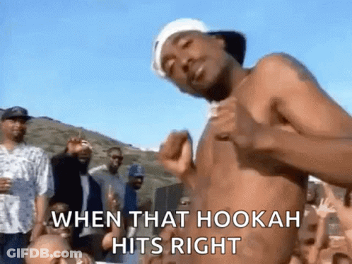 A Man Without A Shirt Is Dancing In Front Of A Crowd Of People . GIF