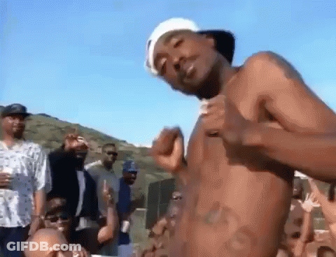 A Man Without A Shirt Is Dancing In Front Of A Crowd Of People . GIF