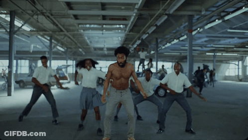 A Man Without A Shirt Is Dancing With A Group Of People In White Shirts GIF