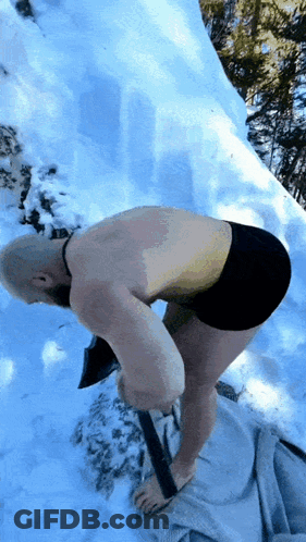 A Man Without A Shirt Is Digging In The Snow With An Axe GIF