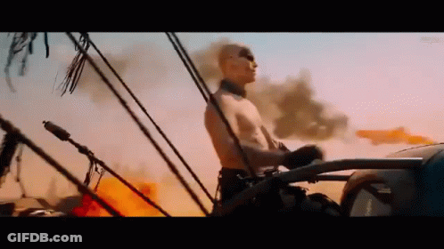 A Man Without A Shirt Is Driving A Car Through A Desert . GIF
