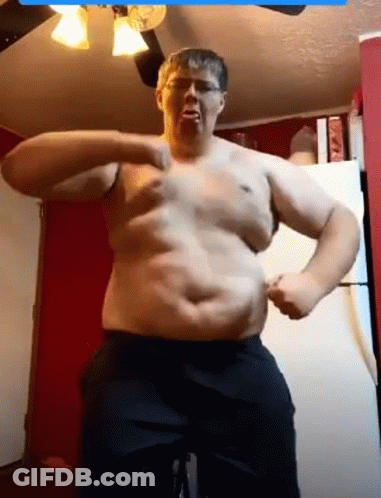 A Man Without A Shirt Is Flexing His Muscles In A Kitchen . GIF