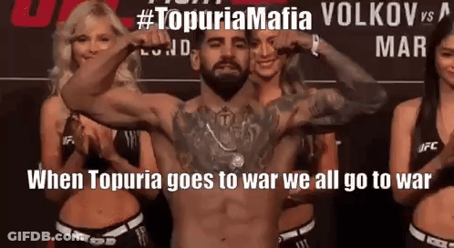 A Man Without A Shirt Is Flexing His Muscles In Front Of Three Women . GIF