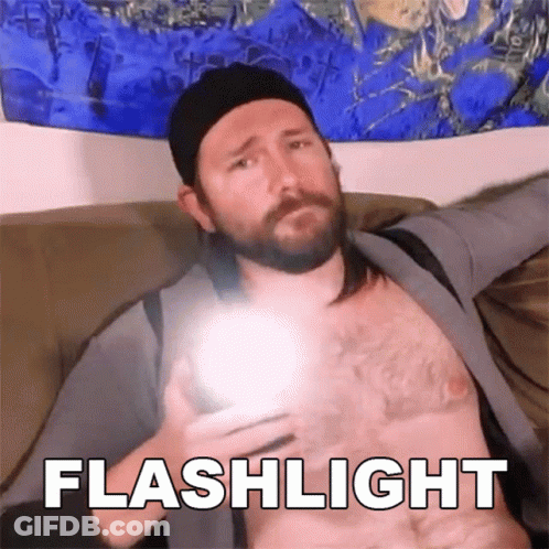 A Man Without A Shirt Is Holding A Flashlight In His Hand And The Word Flashlight Is Above Him GIF