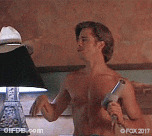 A Man Without A Shirt Is Holding A Gun In Front Of A Lamp .. GIF