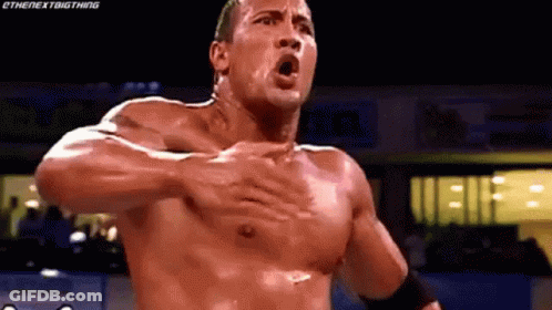 A Man Without A Shirt Is Holding His Chest In A Wrestling Ring . GIF