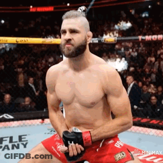 A Man Without A Shirt Is Kneeling Down In A Boxing Ring Holding A Pair Of Gloves . GIF
