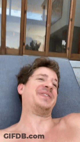 A Man Without A Shirt Is Laying On A Lounge Chair Making A Funny Face GIF