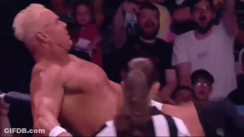 A Man Without A Shirt Is Laying On The Ground In Front Of A Crowd . GIF