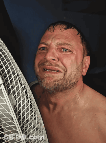 A Man Without A Shirt Is Leaning Against A Fan With His Eyes Closed GIF