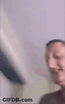 A Man Without A Shirt Is Making A Funny Face While Holding A Book In His Hand . GIF