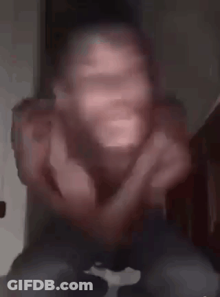A Man Without A Shirt Is Making A Funny Face While Sitting On A Bed . GIF