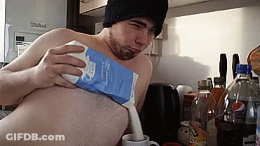 A Man Without A Shirt Is Pouring Milk From A Carton GIF