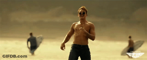A Man Without A Shirt Is Running On A Beach With Top Gun America Written On The Bottom Right GIF