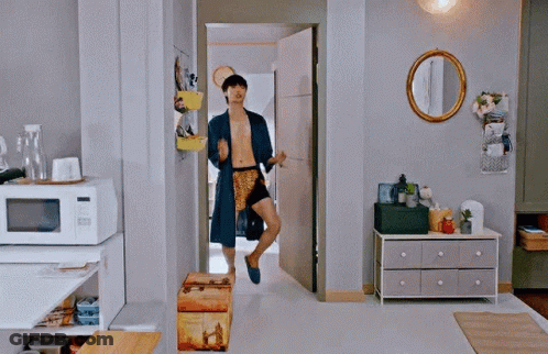 A Man Without A Shirt Is Running Through A Living Room In A Robe . GIF