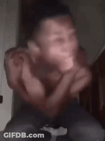 A Man Without A Shirt Is Sitting Down With His Arms Outstretched And His Eyes Glowing In The Dark . GIF