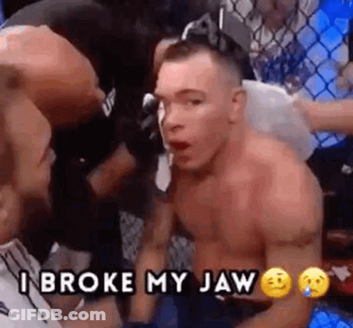 A Man Without A Shirt Is Sitting In A Boxing Ring With Another Man And Says `` I Broke My Jaw '' . GIF